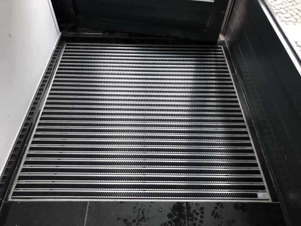 Eine schwarze Eingangsmatte schützt die Eingänge der Gebäude, indem sie Feinschmutz und Feuchtigkeit aufhält