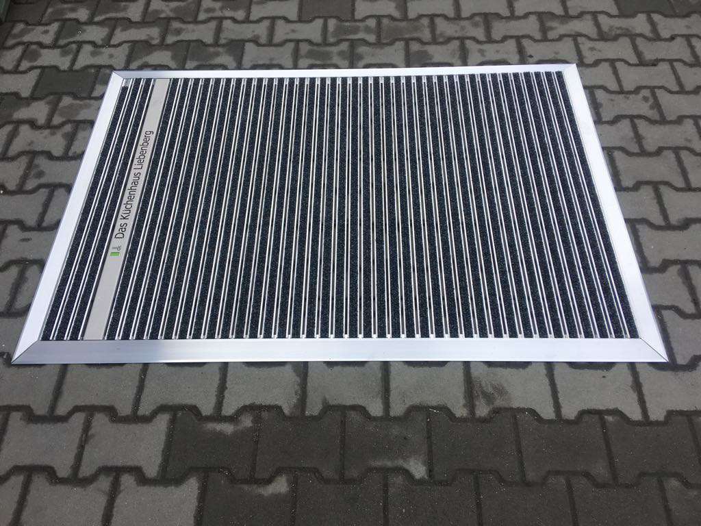 Ein Aluminium Winkelrahmen, der an die Aufbauhöhe des Schuhabstreifers angepasst ist, vermittelt ein Gefühl von Festigkeit und Eleganz.
